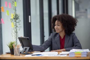 Young African American businesswoman working with pile of documents at office workplace, business finance and accounting concepts.