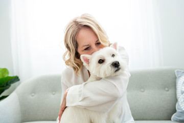 Cheerful retired senior woman with dog and enjoying time with pet at home