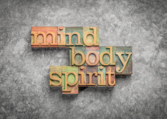 body, mind and spirit - words in wood letterpress printing blocks against textured paper, holistic wellness and lifestyle concept