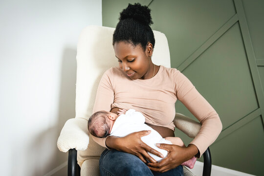A black woman breast feeding her child girl at home