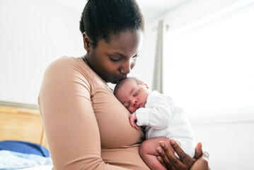 A Portrait of a beautiful black mother, with her nursing baby close to a window