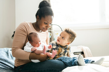 A Portrait of a beautiful black mother, with her nursing baby and child boy - obrazy, fototapety, plakaty