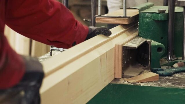 Carpenter works on the jointer-planer or surface planer with wooden plank.  Woodworking machine producing elements for furniture. Сarpentry shop, lumber manufacture