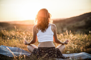 Fototapeta na wymiar woman meditating outdoors at sunset