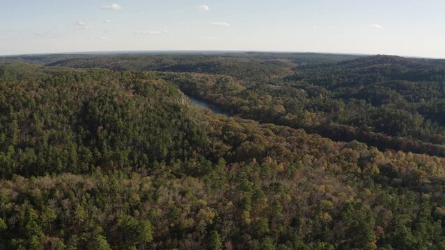 Aerial view of southeastern Oklahoma fall foliage landscape with Mountain Fork River near Broken Bow Lake and Hochatown during golden hour sunset - 4K Drone
