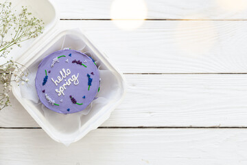 Plastic lunchbox with delicious bento cake Hello spring on white wooden background, copy space.