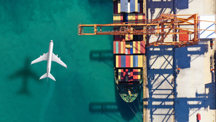 Aerial drone top down concept photo of container terminal and plane flying above indicating popular...