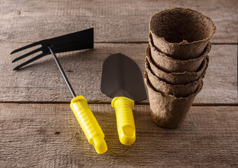 peat cups for planting seeds with a rake and a shovel on a wooden background, the concept of...