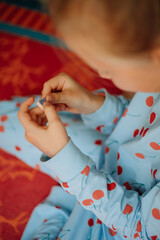 Little girl playing with colourful blocks, girl's hands holding coloured stone, cute little girl in blue pyjama playing at home