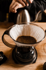 Clever coffee dripper with pour over filter with ground coffee in the funnel in focus. Drip filter coffee brewing. Pour over alternative method of pouring water over coffee beans contained in filter.