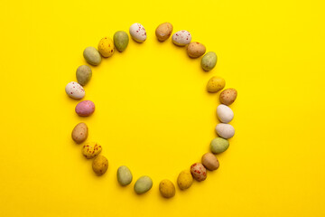Colorful Easter eggs lie around on a yellow background