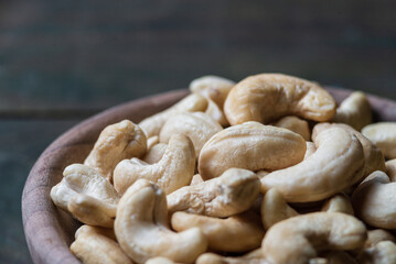 Bowl with raw cashew organic nuts peeled on wooden table rustic table, healthy vegetarian vegan snack Indian walnut Anacardium occidentale sackcloth close-up.