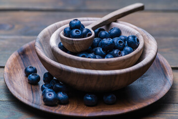 wood spoon ripe sweet blueberry bowl on dark rustic wooden table. Fresh blueberries background with copy space for your text. Vegan and vegetarian concept.  Delicious Fresh Close up antioxidant fruit.