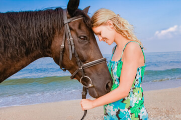 Happy pregnant woman with a horse on the beach in the summer on the nature