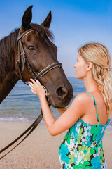 Obraz premium Happy pregnant woman with a horse on the beach in the summer on the nature
