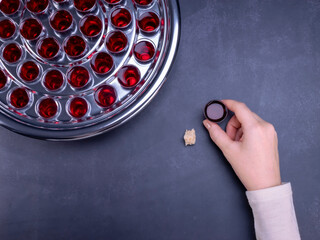 Closeup of young woman taking communion from small cups on black background