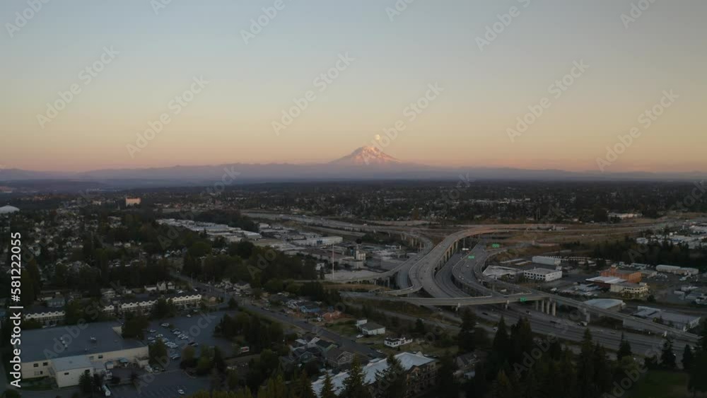 Wall mural Aerial view of Mount Rainier, Washington during sunset with the moon rise above it and Seattle suburbs in the foreground - 4K Drone - Wall murals