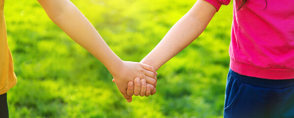 Children walk together holding hands. Selective focus.