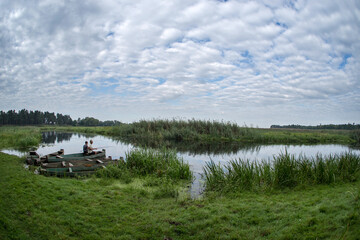 Two men are fishing with rods in the river from boats on the boat dock.