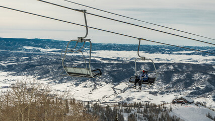 Fototapeta na wymiar Skier on ski lift in Steamboat Springs, Colorado ski resort landscape