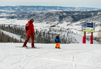 Father and son skiing down ski runs in Steamboat Springs, Colorado ski resort mountain town