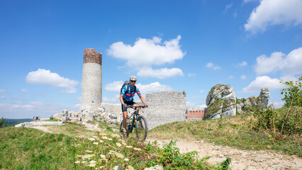 A man on a mountain bike on the hill of Olsztyn Castle. Poland.	