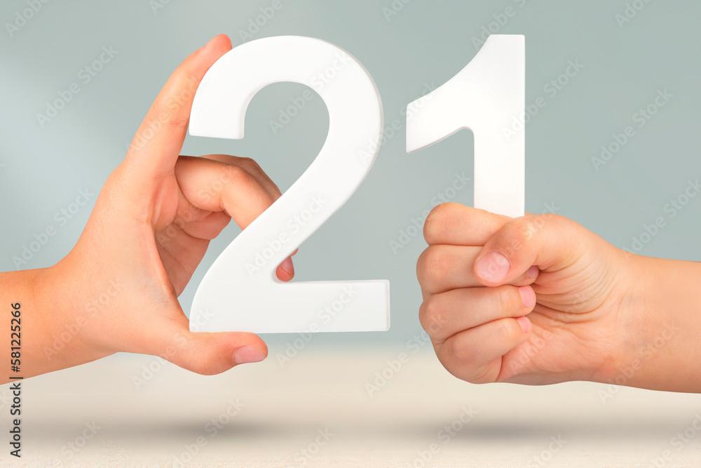 Aufkleber Number two one in hand. Hand holding white number 21 on blurred background with copy space. Concept with number twenty one. 21 percent, birthday 21, twenty one