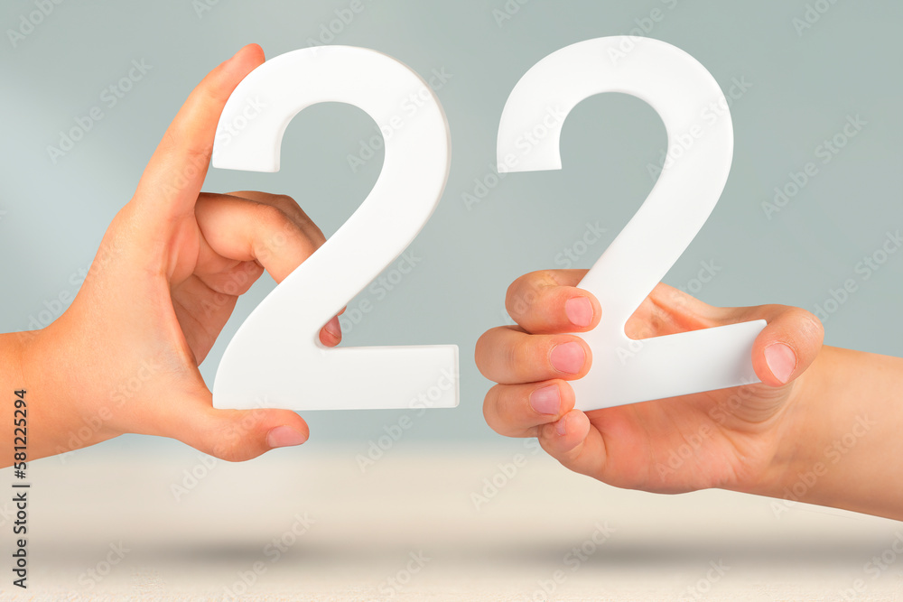 Fototapete number two two in hand. hand holding white number 22 on blurred background with copy space. concept 