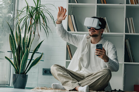 young man at home with virtual reality glasses and mobile phone