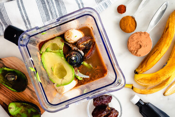 Overhead View of Coffee-Mocha Smoothie Ingredients in a Blender: Avocado, banana, cacao powder, and other smoothie ingredients in a blender pitcher