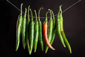 Green chili peppers hanging on a natural rope on a brown background