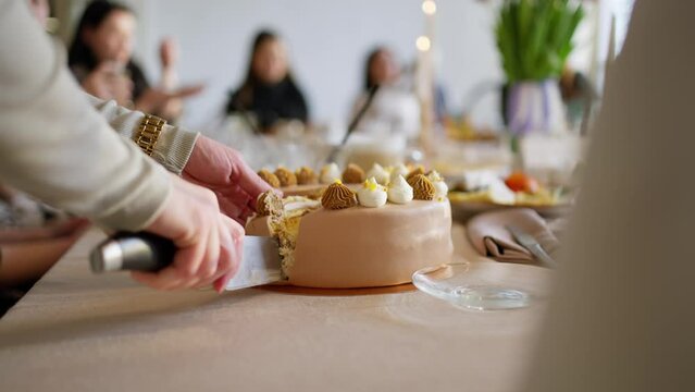 Female hands cut off a piece of festive cake with a knife