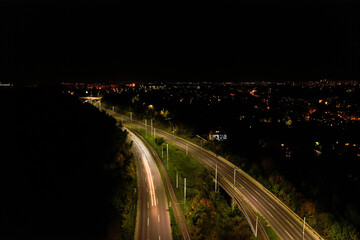 Fototapeta na wymiar Top down view to road. Romantic night aerial photo of cars traveling. The light on the road at night in city. Background scenic road drone view. Tram railways