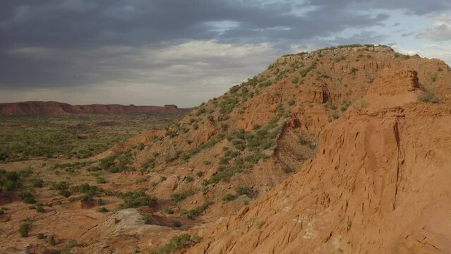 Revealing view of Caprock canyons state park in west Texas landscape at sunset and golden hour with thunderstorm in the distance - 4K Drone