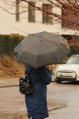 A woman with an umbrella walks on a rainy day