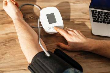 Close-up of a man's hands measuring his blood pressure with a special cuff and tonometer. Health...