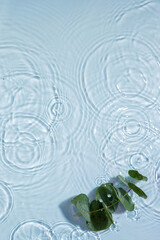 Blue water texture, surface with rings and ripples. Green leaves on water surface. Spa concept...