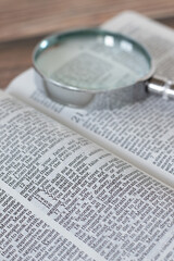 A closeup of the ten commandments verses in an open holy bible book with a magnifying glass....