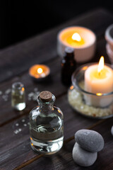 Spa setting with essential oil, candle, sea salt, pebbles, towel on dark wooden background. Massage, aromatherapy. Natural organic ingredients for relaxation, detention. Wellness in salon concept