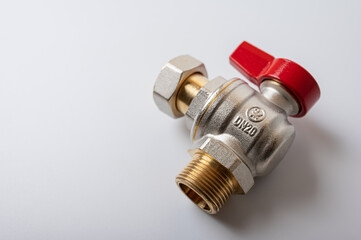 brass metal water faucet with red valve, different angle isolated on light background close up, plumbing connection