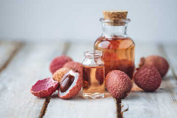 Glass bottles with pure organic essential litchi oil on wooden background. Concept of natural ingredients for beauty treatment, skin care, massage. Exotic fruit extract