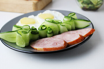 ham sausage with cucumber salot and barley on a grey plate. breakfast healthy hearty delicious food nutritious