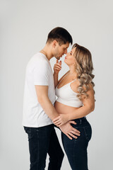 a couple waiting for a child in white T-shirts and jeans on a white background.