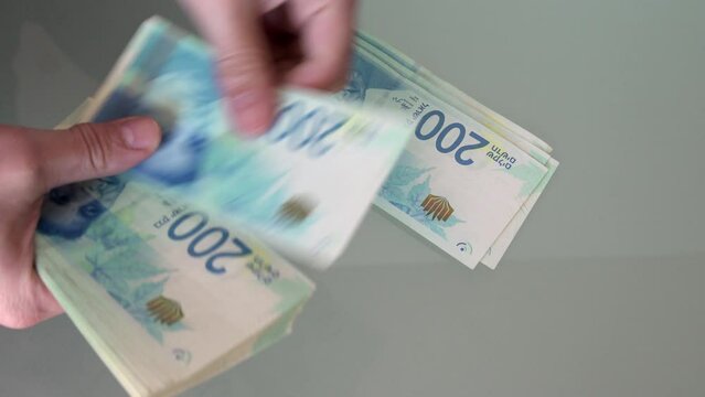 Hands Counting New Shekels bills, cash banknotes, above, close-up.