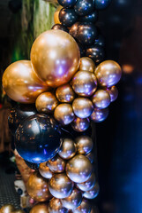 Background, texture of round black, golden balloons on the photo zone against the background of the wall. Photography, holiday, birthday, wedding.