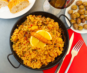 Appetizing racy paella with seafoods, green peas and bell pepper served with lemon slice.Traditional Valencian cuisine