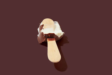 Bitten chocolate ice cream on a stick brown pastel background