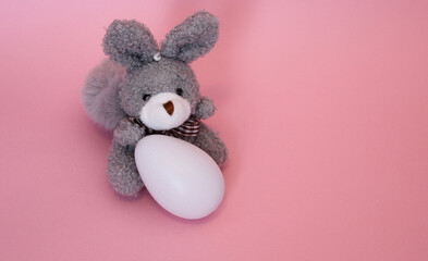 Conejo pequeño gris de felpa con huevo blanco. 