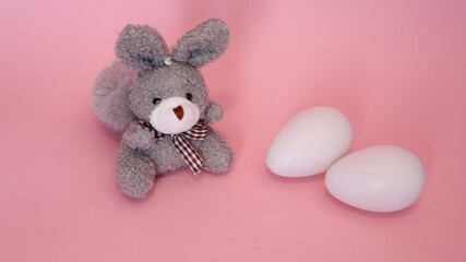 Conejo gris pequeño con huevos blancos de plastico. 