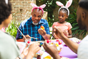 Happy african american family coloring easter eggs in garden